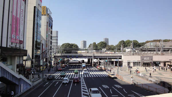 a wide street with stores on one side and Ueno Station on the right